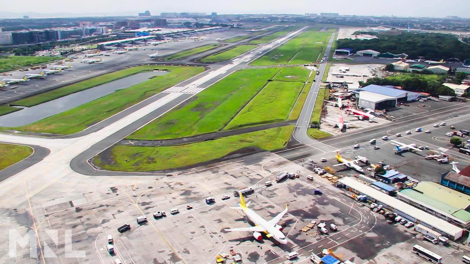 The main runway of Ninoy Aquino International Airport, seen from the air, with the terminals and the city beyond it.